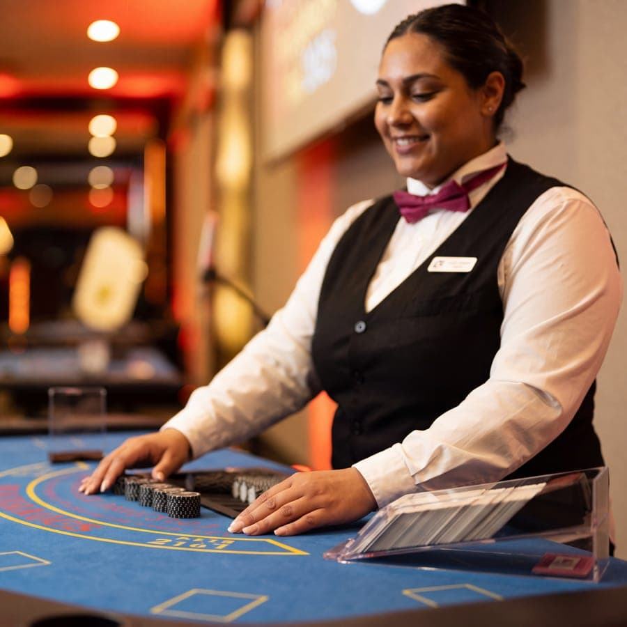 Smiling Echo dealer squaring a stack of chips on the blackjack table