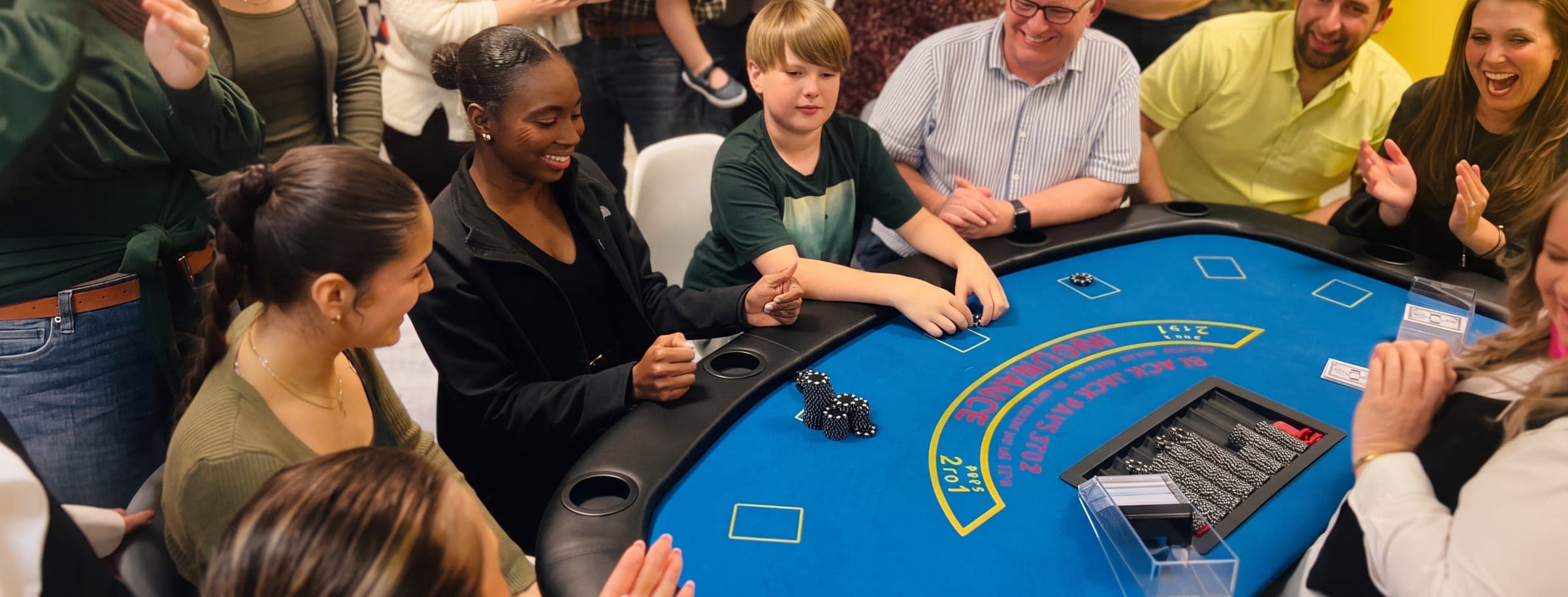 Players and cheering onlookers around a blackjack table, chips on the felt
